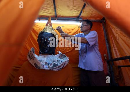 Bangkok, Thailandia. 15 luglio 2025. Un membro del personale applica una vernice dorata alla statua di Buddha al tempio Wat Pho a Bangkok, Thailandia, 15 luglio 2025. Il tempio Wat Pho è uno dei più magnifici complessi di templi buddisti di Bangkok. Crediti: Rachen Sageamsak/Xinhua/Alamy Live News Foto Stock