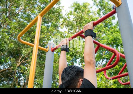 Uomo che si allena sulla barra d'acciaio del parco. Vista posteriore. Foto Stock