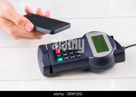 Il design piatto mostra che lo smartphone tocca il terminale di pagamento su un piano bianco, pagamenti senza contatto Foto Stock