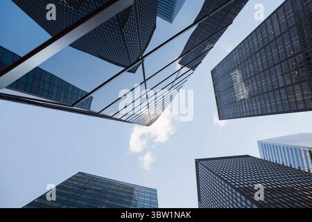Torri di vetro per ufficio che formano il canyon a livello della strada, riflettendo la luce del sole sulle strutture a griglia Foto Stock