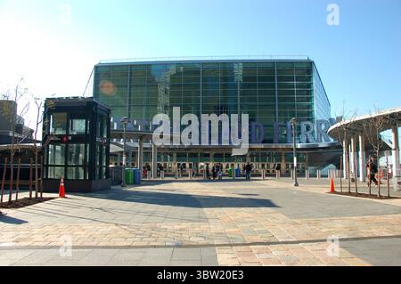 Moderno terminal dei traghetti di Staten Island a New York in una giornata di sole, con persone che camminano e riflessi sulla facciata di vetro Foto Stock