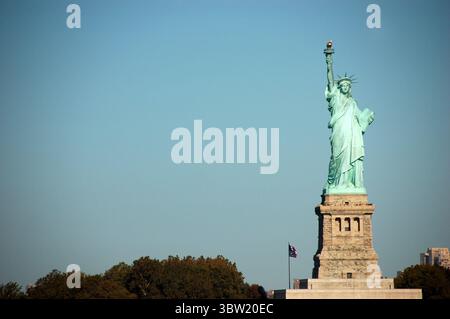 La Statua della libertà, che si erge a Liberty Island a New York, è stata catturata in una giornata limpida e soleggiata con uno sfondo blu Foto Stock