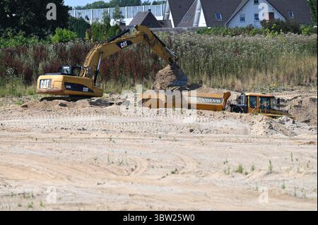 Kaarst, Germania. 15 luglio 2025. Un escavatore carica la sabbia su un camion ribaltabile in un lago di cava il 15 luglio 2025 a Kaarst, Germania. Credito: dpa/Alamy Live News Foto Stock