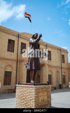 Un'impressionante statua a Baghdad simboleggia il patrimonio culturale, adagiato contro l'architettura tradizionale e un cielo luminoso. Foto Stock