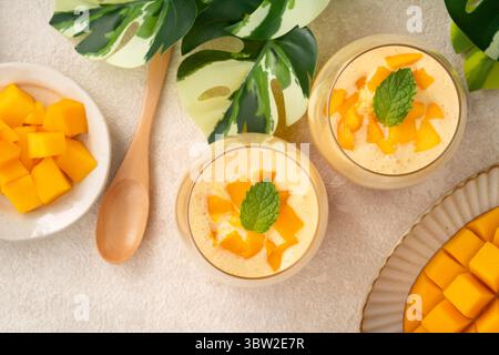 Dessert rinfrescante alla mousse di mango servito in tazze di vetro, ricoperto di foglie di menta, perfetto per l'estate. Foto Stock