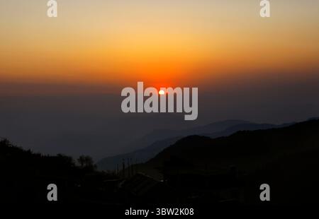Un tramonto mozzafiato dipinge il cielo in tonalità calde su creste di montagna stratificate. Il sole si tuffa dietro le vette lontane, generando un bagliore tranquillo sulla Los Angeles Foto Stock