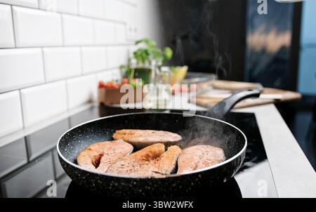 Frittura e cottura a vapore del salmone di pesce rosso in Una padella sul fornello da cucina Foto Stock