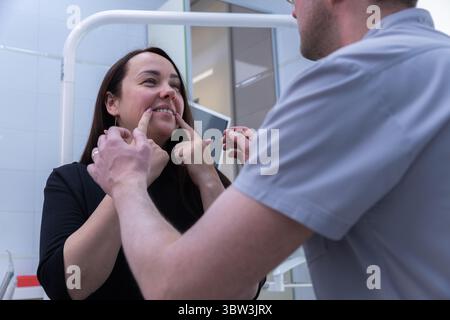 Un'interazione delicata: Un paziente che interagisce con un professionista in un ambiente odontoiatrico o medico, sottolineando l'importanza della cura del paziente Foto Stock