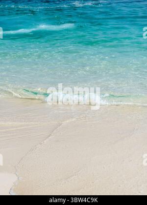 Sfondo di un primo piano di acque cristalline con piccole onde turchesi su una spiaggia dell'isola di Zanzibar in Tanzania Foto Stock