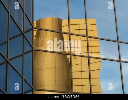 Riflesso distorto di un edificio giallo nelle finestre a specchio di un edificio per uffici Foto Stock
