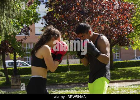 Pugili professionisti allenamenti di coppia all'aperto, giovane atleta donna e uomo latino Foto Stock