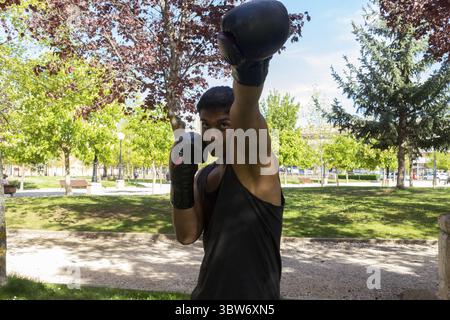 Pugile latino che si allena all'aperto con un pugno alto Foto Stock