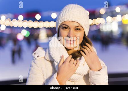 Una donna sulla pista sta pattinando e prendendo selfie su smartphone. Capodanno e Natale. Fata luci. Concetto di umore su ghiaccio e neve. Inverno Foto Stock