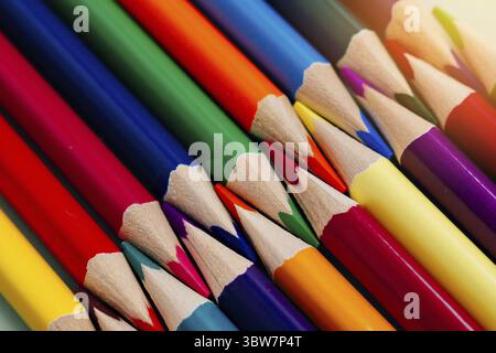 Le matite colorate affilate si trovano in un primo piano di fila. Solido sfondo astratto di matite multicolore in legno. Queste sono forniture scolastiche Foto Stock
