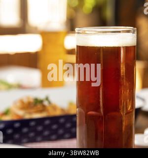 Bicchiere di birra scuro con piatto da vicino Foto Stock