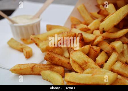Primo piano di patatine belghe dorate che mostrano una consistenza croccante e un aspetto rustico. Un popolare spuntino di strada dal Belgio, fotografato alla luce naturale. Foto Stock