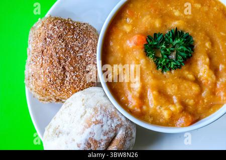 Londra Regno Unito, 16 luglio 2025, Una ciotola di zuppa calda di lenticchie guarnita con prezzemolo e panini Foto Stock