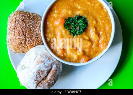 Londra Regno Unito, 16 luglio 2025, Una ciotola di zuppa calda di lenticchie guarnita con prezzemolo e panini Foto Stock