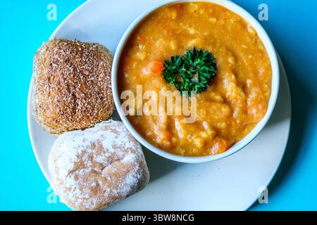 Londra Regno Unito, 16 luglio 2025, Una ciotola di zuppa calda di lenticchie guarnita con prezzemolo e panini Foto Stock