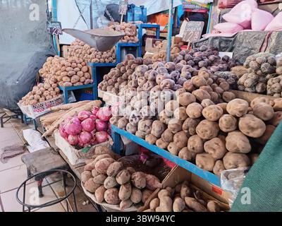 Un mercato alimentare in Perù con patate crude in primo piano, pronte per la vendita, e cartelli indicanti i prezzi di ciascun prodotto. Foto Stock