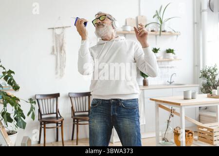 Buon uomo anziano che balla mentre ascolta la musica con le cuffie - anziani attivi e divertimento dance mood Foto Stock