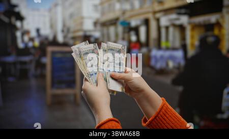 Donna che tiene in mano suole peruviane su una terrazza urbana all'esterno di una caffetteria, illustrando transazioni finanziarie e affari in una città all'aperto Foto Stock