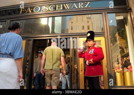 Una persona vestita con un costume da schiaccianoci accoglie i clienti di fronte al negozio di giocattoli FAO Schwarz al Rockefeller Center di Manhattan, New York City. Foto Stock