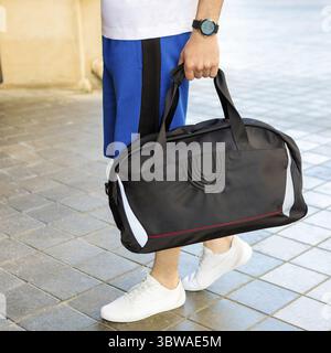Giovane uomo che tiene una borsa nera da vicino Foto Stock