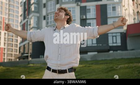 Il giovane danzatore caucasico celebra il divertimento in movimento ascolta musica weekend energico ragazzo felice uomo d'affari uomo in città all'aperto divertirsi ballare Foto Stock