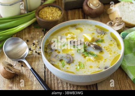 Concetto di alimentazione sana e dietetica. Zuppa di crema di funghi con bulgur e panna sul tavolo rustico Foto Stock