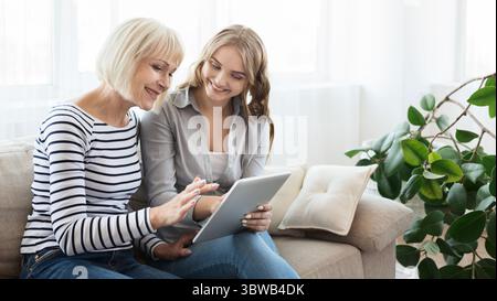 Figlia che insegna alla madre anziana di usare il tablet Foto Stock