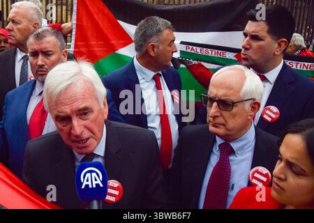 Londra, Regno Unito. 4 giugno 2025. Il deputato John McDonnell parla ai media mentre il deputato Neil Duncan-Jordan guarda durante una protesta pro-Palestina fuori dalle camere del Parlamento chiedendo un embargo sulle armi contro Israele, che Israele interrompe i suoi attacchi a Gaza e che gli aiuti vengono erogati alla popolazione affamata. Centinaia di manifestanti tenevano un lungo tessuto rosso intorno al parlamento, simboleggiando le "linee rosse” attraversate da Israele. Crediti: Vuk Valcic/Alamy Live News Foto Stock