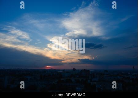 Tramonto colorato con spettacolari nuvole sullo skyline di Dnipro, Ucraina, fotografato da un alto punto panoramico. Edifici sagomati. Grandangolo vi Foto Stock
