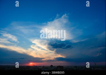 Tramonto colorato con spettacolari nuvole sullo skyline di Dnipro, Ucraina, fotografato da un alto punto panoramico. Edifici sagomati. Grandangolo vi Foto Stock