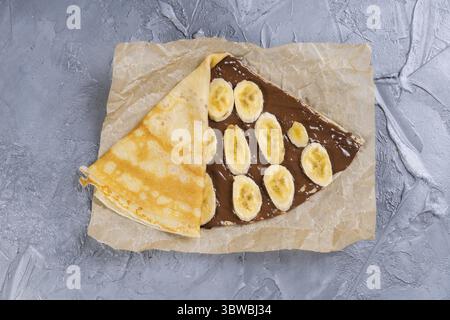 Crepes farcite con crema di cioccolato e banana. Frittelle sottili. Dessert dolce. Cucina francese vista dall'alto Foto Stock