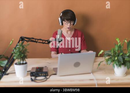 Radio ospite donna di mezza età che fa la registrazione di podcast per lo spettacolo online - broadcast e dj concetto Foto Stock