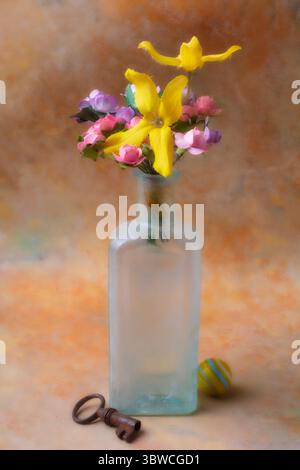 Piccola bottiglia di fiori in vetro con chiavetta e marmo natura morta Foto Stock