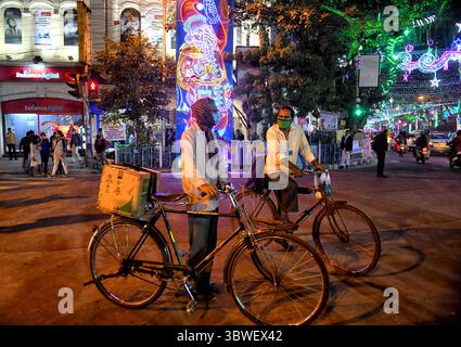24 dicembre 2020, Kolkata, Bengala Occidentale, India: Venditori ambulanti con le loro biciclette visti in attesa di un segnale stradale su una strada decorata durante la vigilia di Natale. (Immagine di credito: © Avishek Das/SOPA Images via ZUMA Wire) Foto Stock