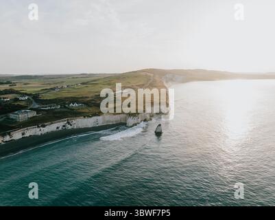 Una splendida vista sull'oceano con una scogliera rocciosa sullo sfondo. Il cielo è limpido e il sole splende Foto Stock