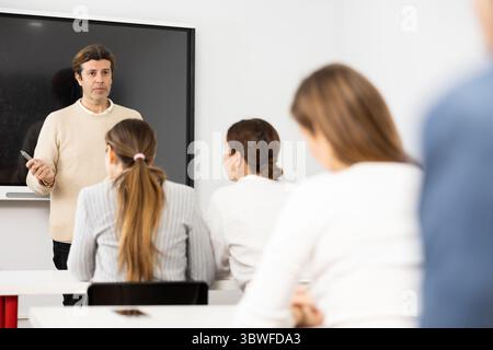 Professore esperto che spiega il soggetto ad aula piena di studenti Foto Stock