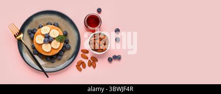 Frittelle dolci con mirtilli, banane, mandorle e miele su sfondo rosa con spazio per il testo, vista dall'alto Foto Stock