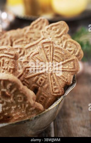 Ciotola di biscotti speculaas, candele dorate sullo sfondo. Dessert per feste natalizie Foto Stock