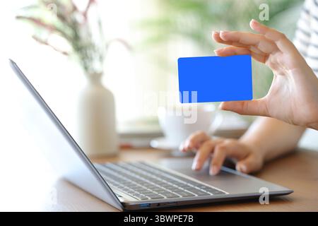 Clos eup ritratto di una donna mano che mostra una carta bianca usando un computer portatile a casa Foto Stock