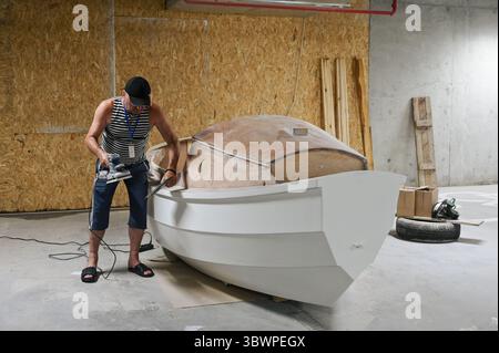 Un uomo lavora su uno yacht presso l'UNBROKEN Center di Leopoli, Ucraina, 16 luglio 2025. Più di 30 pazienti hanno costruito lo yacht da febbraio. Si prevede che la nave sarà varata tra un mese. (Foto di Anastasiia Smolienko/Ukrinform) Foto Stock