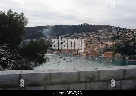 Villefranche-sur-Mer, Francia - 1 gennaio 2010 vista panoramica della baia con edifici colorati e distanti forti collinari in una giornata nuvolosa nel Sud Foto Stock