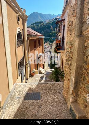 Affascinante vicolo a Scilla, Calabria, Italia, con case tradizionali e una vista panoramica sulle montagne. Foto Stock