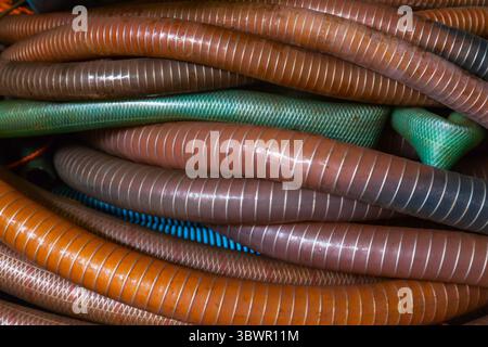 Un mucchio di tubi flessibili in plastica con una treccia metallica all'interno, primo piano. Foto Stock