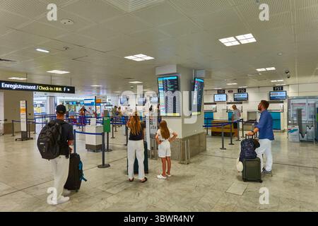 I viaggiatori presso un'area check-in aeroportuale che osserva le informazioni sulla partenza Foto Stock