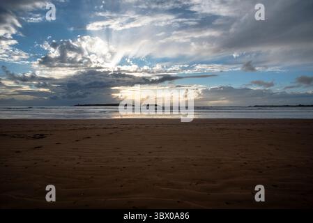 Tramonto sulle vaste spiagge di Essaouira con cieli blu, nuvole bianche e onde che si infrangono sulla riva del Marocco Foto Stock