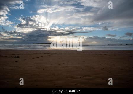 Tramonto sulle vaste spiagge di Essaouira con cieli blu, nuvole bianche e onde che si infrangono sulla riva del Marocco Foto Stock